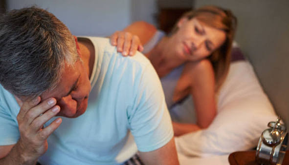 Couple in bed, man awake and frustrated