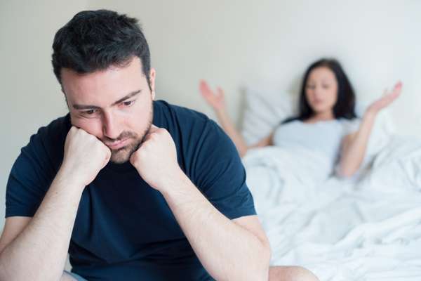 Man sitting on the edge of a bed looking discouraged